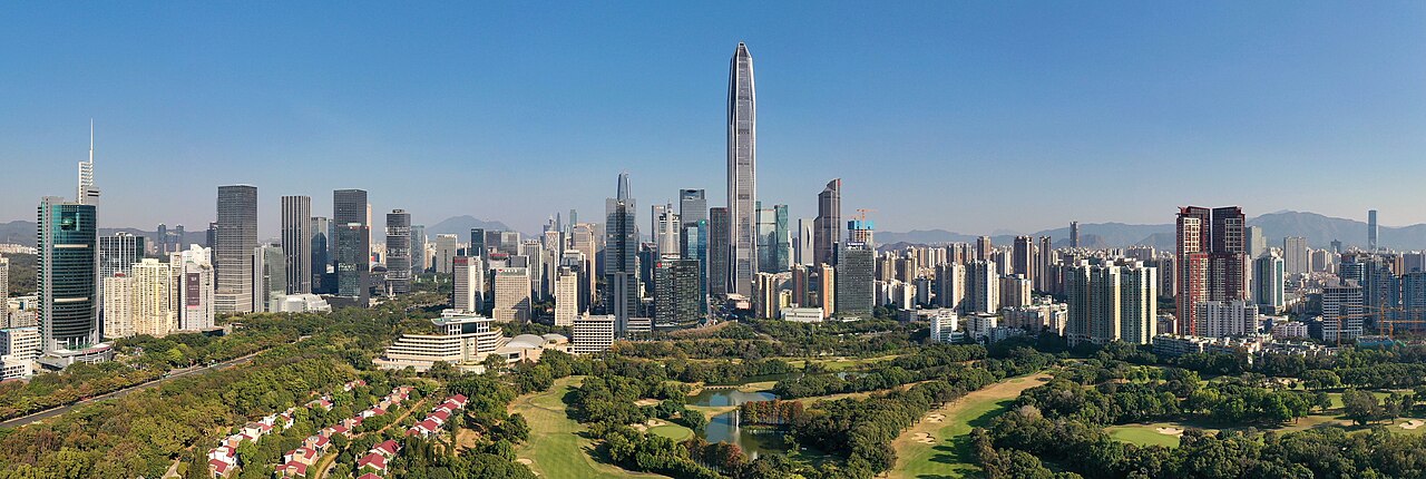 Panoramic view of the Shenzhen Futian district skyline with dense high-rise buildings, the Ping An Finance Centre tower, and low-rise residential villas in the foreground